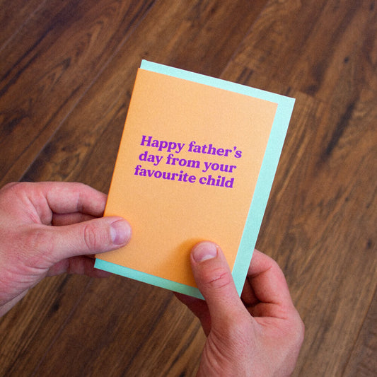 Sprinkle Club - A man holding an funny orange Father's Day card that says 'Happy Father's Day from your favourite child'