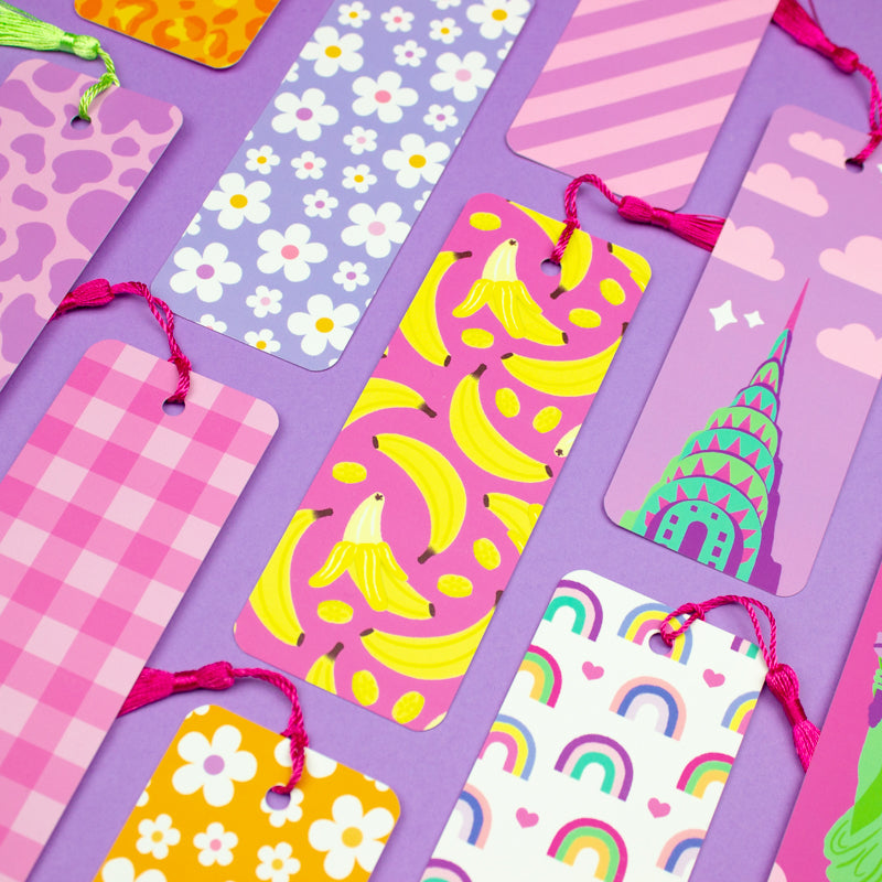 A selection of bookmarks with various patterns including clouds, flowers, bananas, and rainbows, each featuring a pink tassel