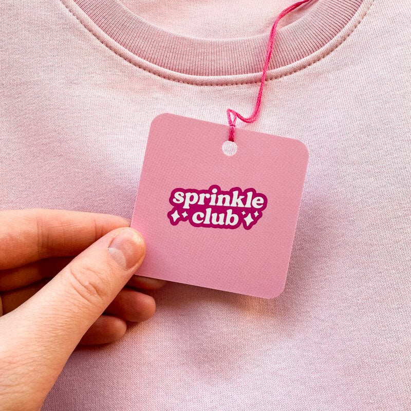 Sprinkle Club - A pink sweatshirt with a pink swing tag attached