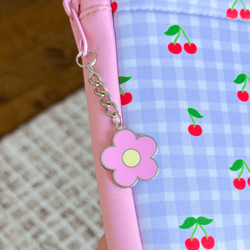 Sprinkle Club - Pink flower charm attached to a book sleeve with a blue gingham background featuring red cherries