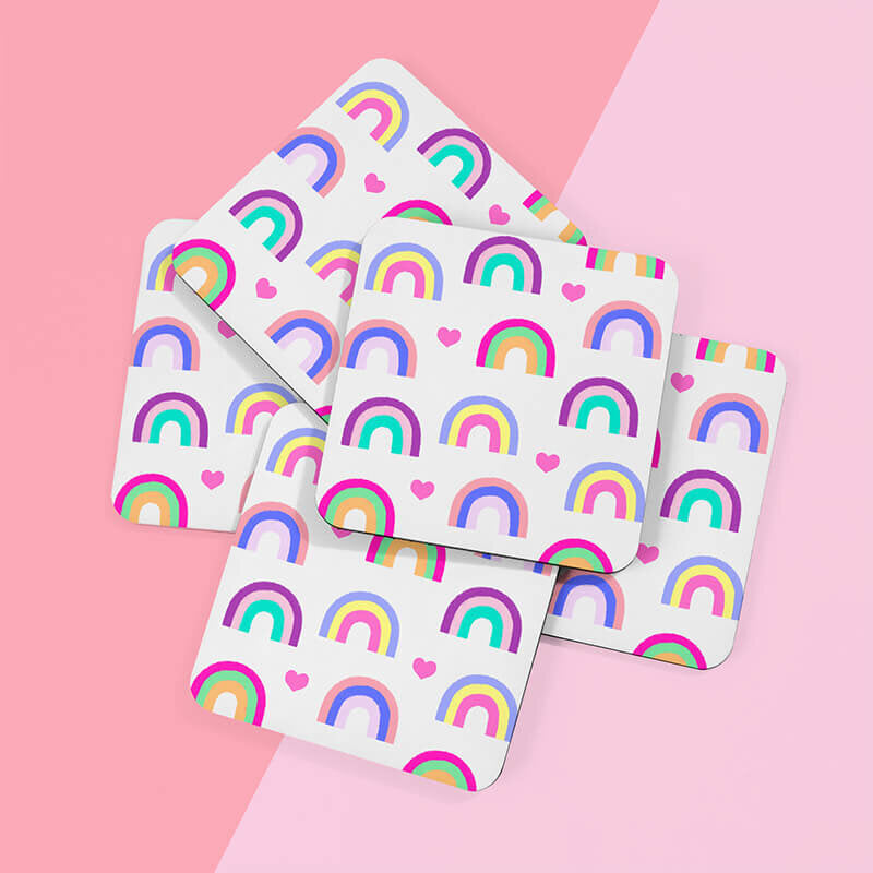 Sprinkle Club - A stack of white square drinks coasters adorned with rainbow and heart patterns, placed on a pink background
