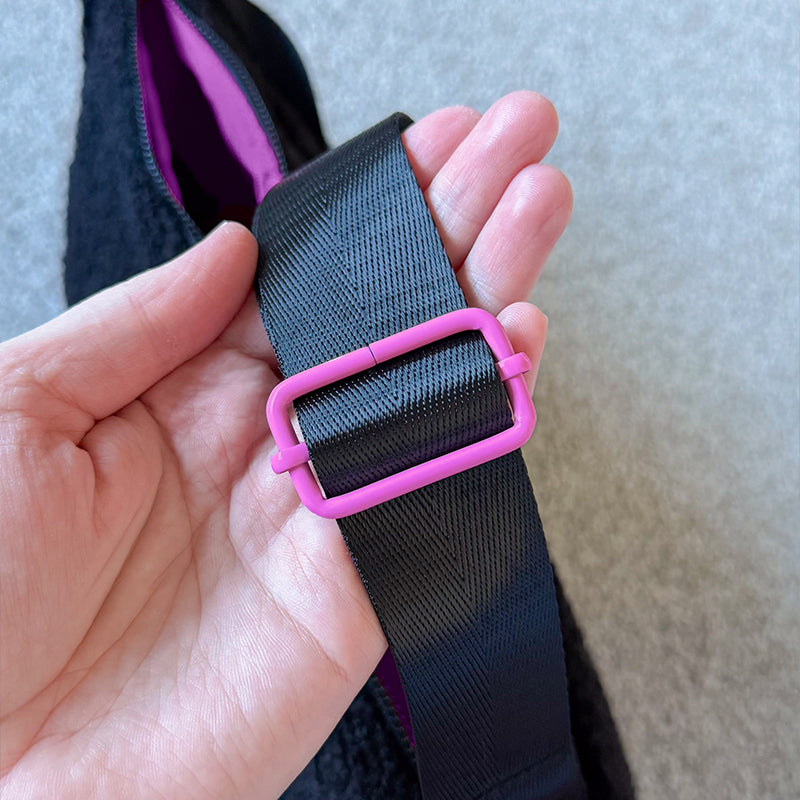 Sprinkle Club - Close-up of the black adjustable bag strap with pink hardware, held against a black sherpa Sprinkle Club bag
