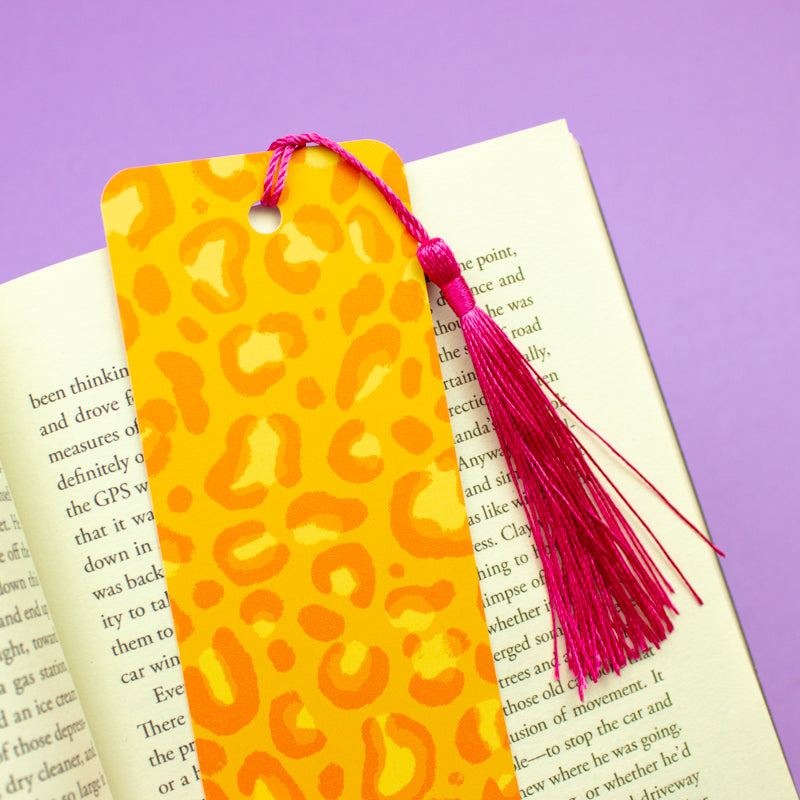 Sprinkle Club - A bright orange bookmark with a leopard print design, finished with a vivid pink tassel