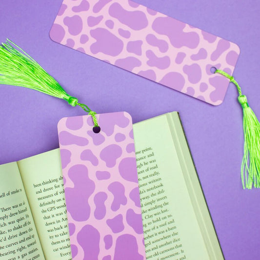 Sprinkle Club - A lilac bookmark with a cow print pattern and a bright green tassel against a purple background