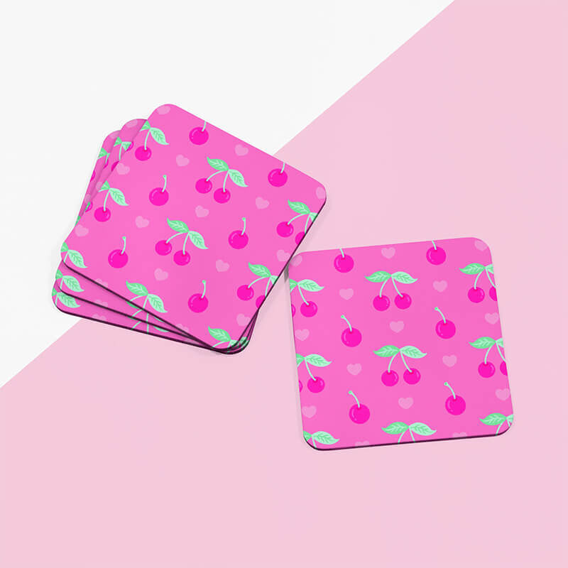 Sprinkle Club - A stack of pink square drinks coasters with cherry and heart designs on a two-tone pink background
