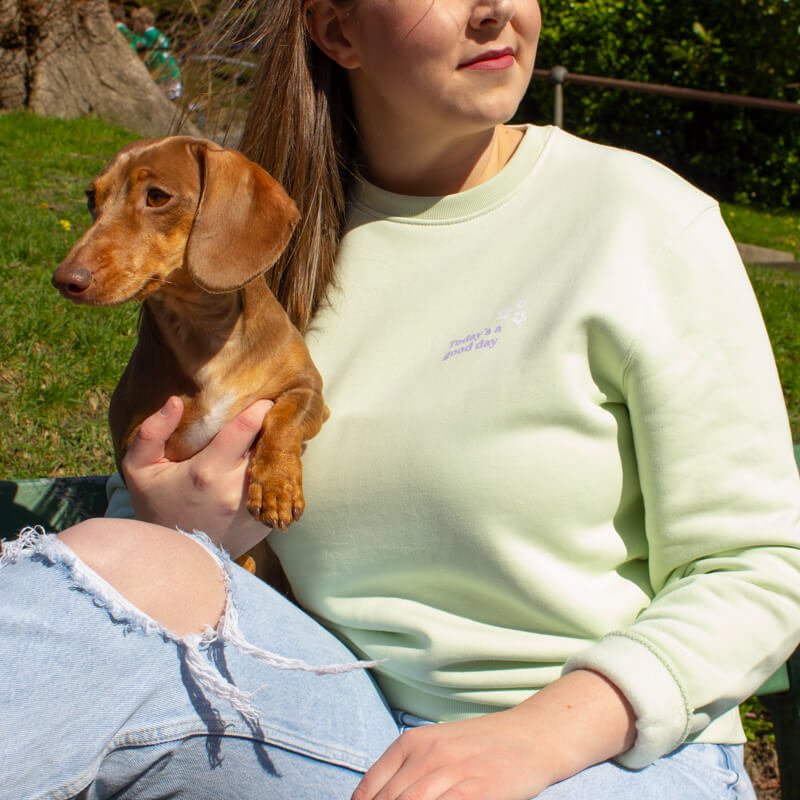 Sprinkle Club - A woman on a walk with her dachshund wearing a mint green pastel sweatshirt