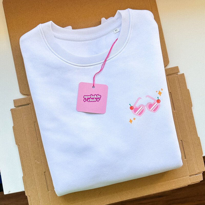 Sprinkle Club - A white folded valentine's sweatshirt with pink love heart sunglasses