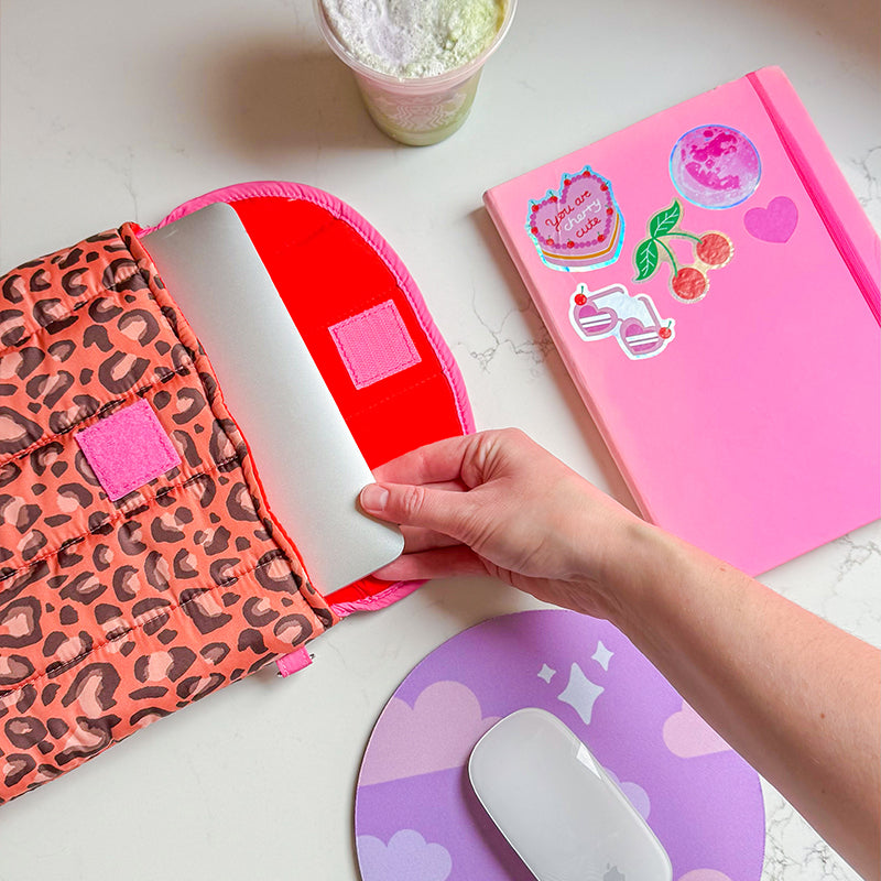 Sprinkle Club - Laptop being placed into a leopard print quilted sleeve with red and pink padded lining