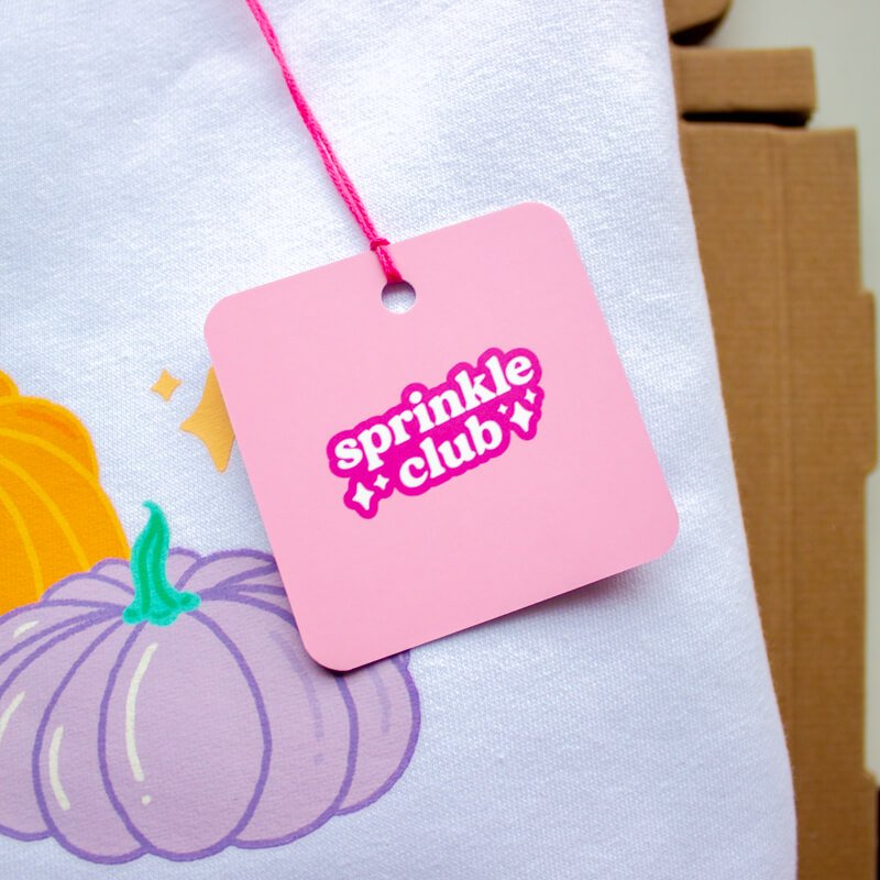 Sprinkle Club - A pink swing tag attached to a cute halloween themed sweatshirt