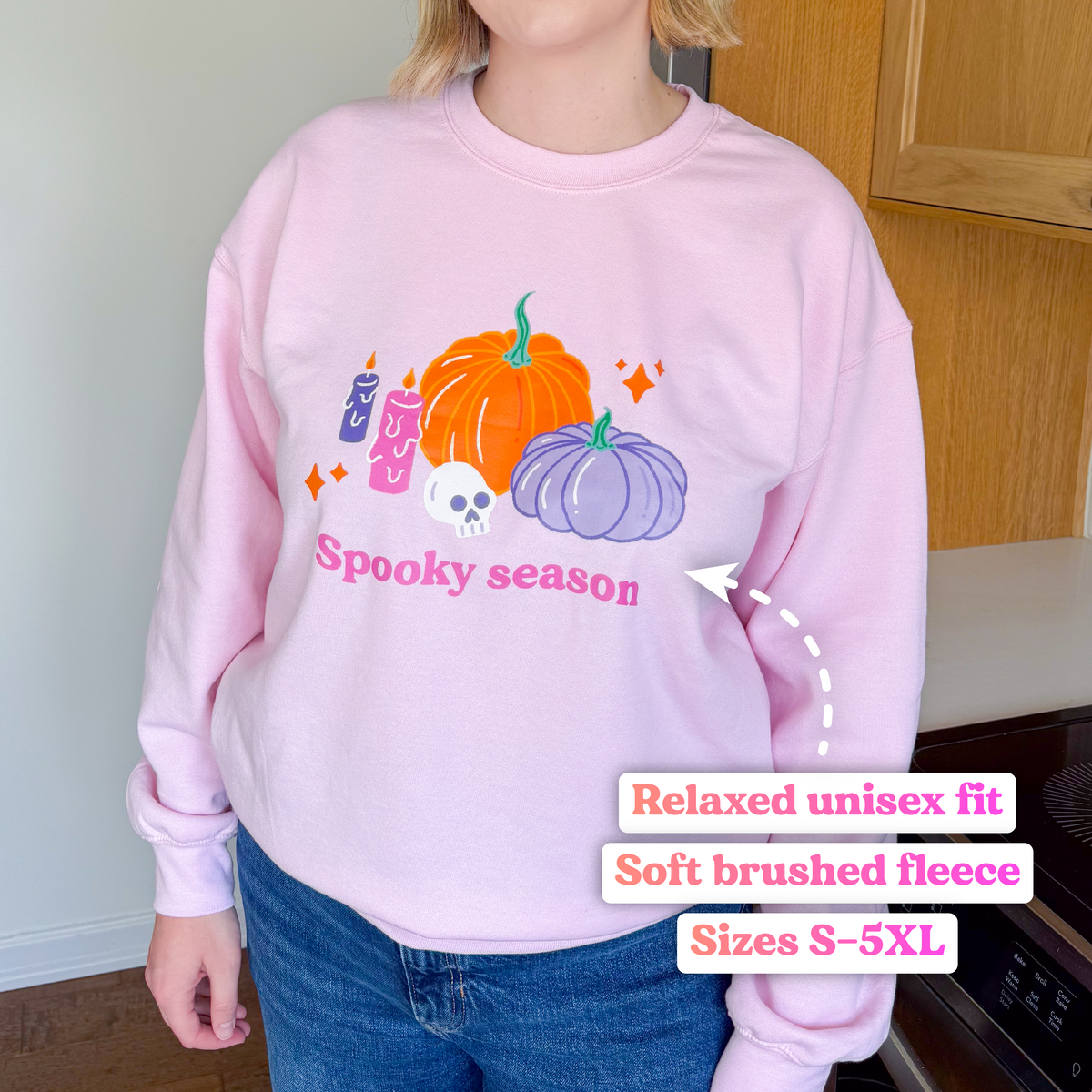 Baby pink pastel Halloween pumpkin sweatshirt worn with jeans, labelled: relaxed unisex fit, soft brushed fleece, sizes S–5XL