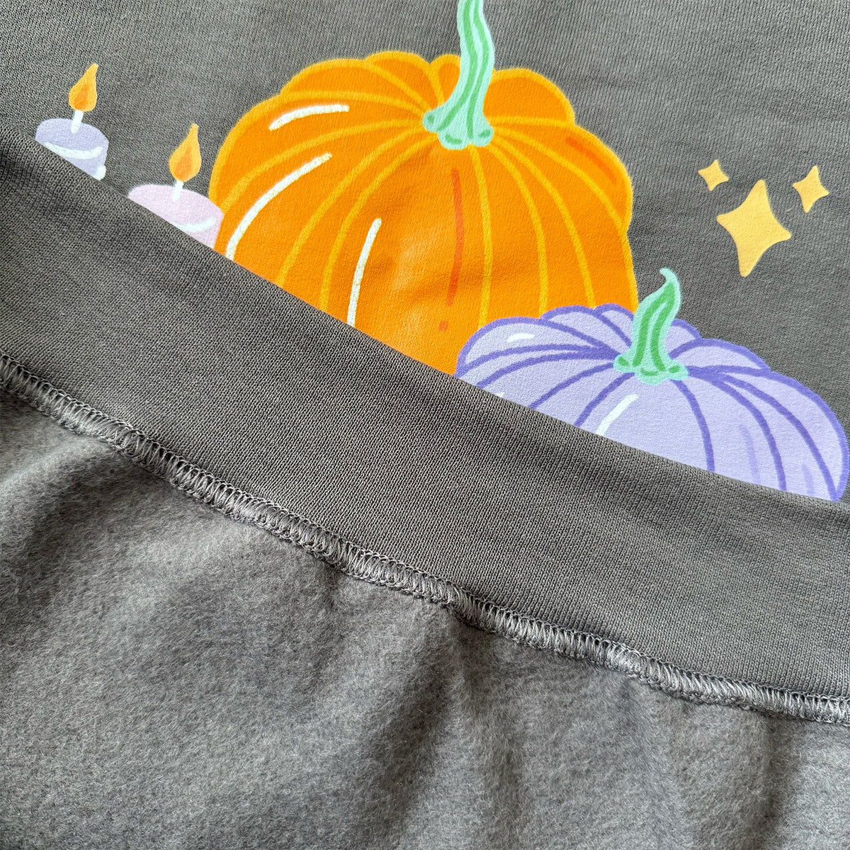 Charcoal pastel Halloween pumpkin sweatshirt folded back to show the soft brushed fleece inside beneath the pumpkin print