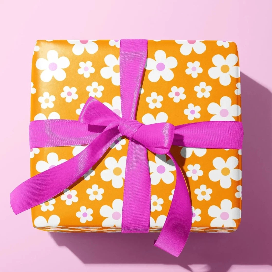 Sprinkle Club - A present wrapped in orange daisy print wrapping paper with a pink bow ribbon