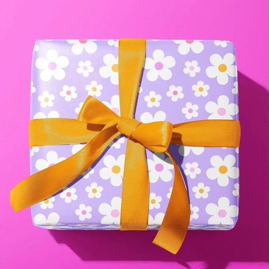 Sprinkle Club - A gift wrapped in lilac and pastel colour daisy wrapping paper with an orange bow