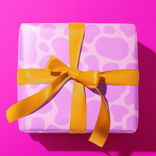 Sprinkle Club - A present wrapped in a lilac wrapping paper with a cow print design
