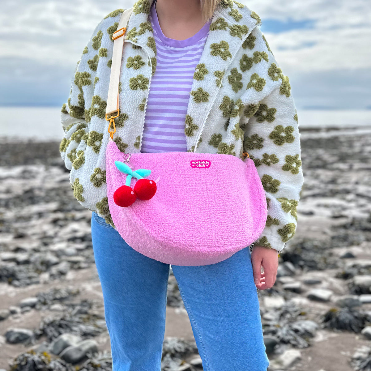 Pink teddy crossbody bag with cherry plushie keychain worn across the body