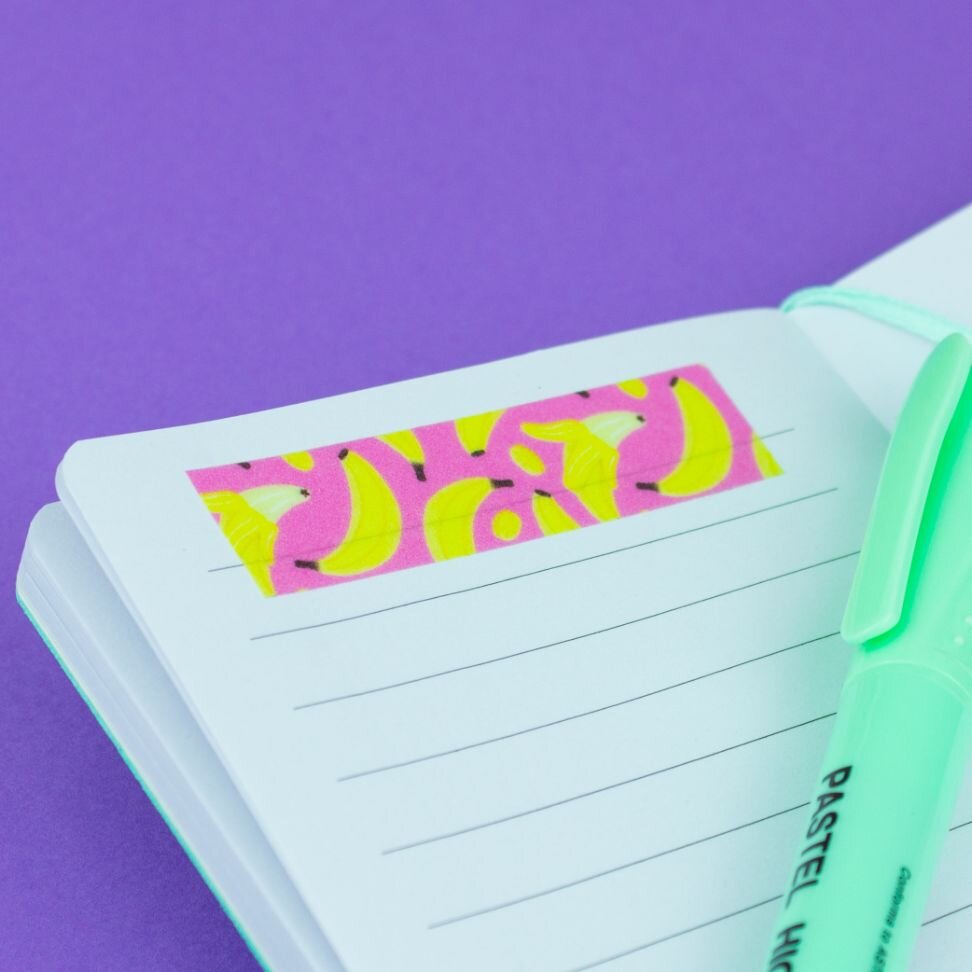 Pink and yellow banana fruit washi tape used as a label on a white notebook page with a pastel green highlighter pen